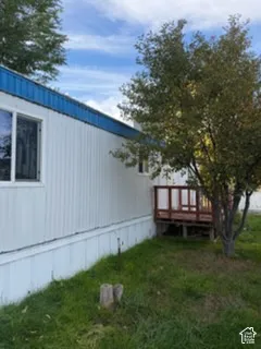 Exterior siding with blue metal trim, elevated wood deck, and mature landscaping
