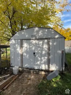 Detached storage shed featuring a gambrel roof and double-door entry
