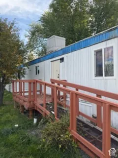Exterior facade featuring vertical siding, a raised wood-finish entry deck, and a wood-finish ramp with railing