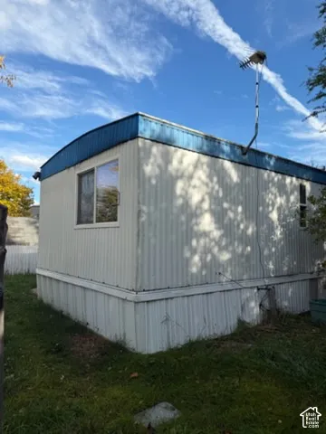 Exterior featuring vertical metal siding, arched roofline, blue trim detailing, sliding windows, and a white fence perimeter