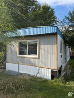 Exterior featuring vertical panel siding, a metal roof with an angled fascia, and a sliding window