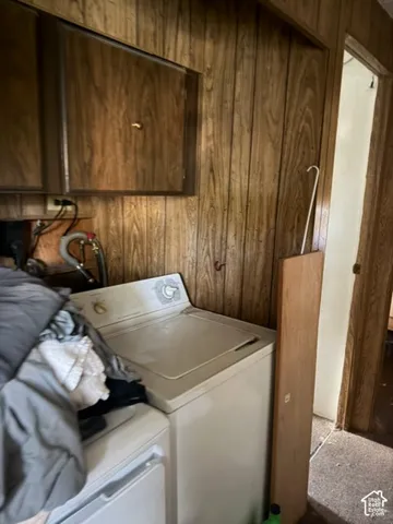 Laundry area featuring wood-paneled walls and overhead cabinetry