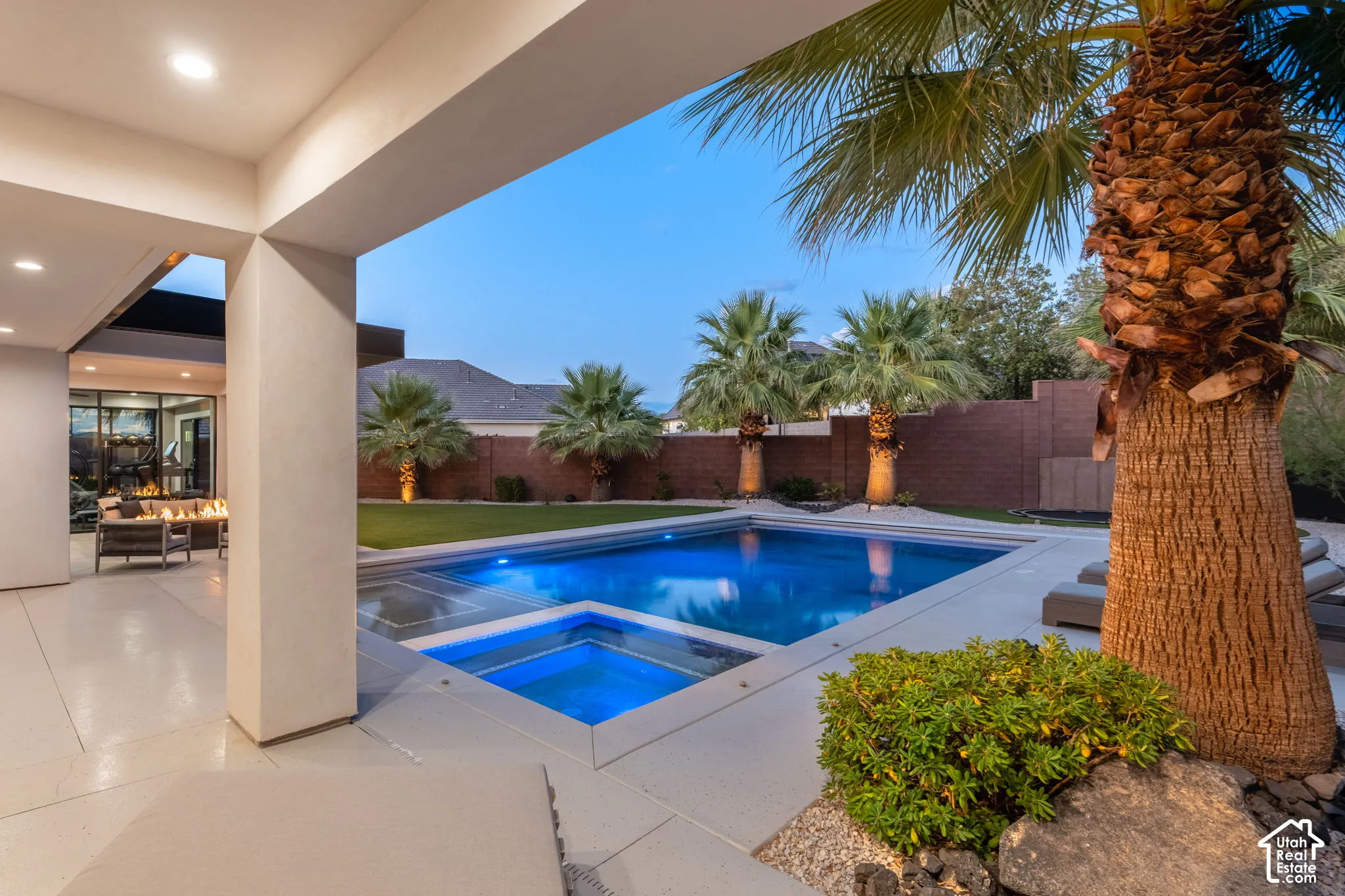 Covered patio with recessed lighting, in-ground pool featuring an integrated spa, concrete decking, and perimeter masonry wall
