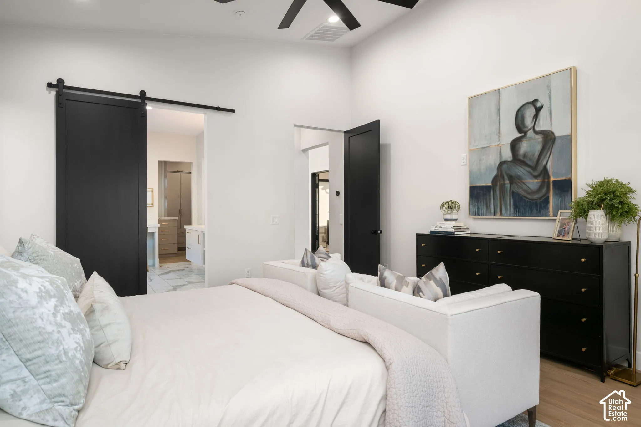 Vaulted ceiling featuring a black ceiling fan, black interior doors, and a black sliding barn door with exposed hardware