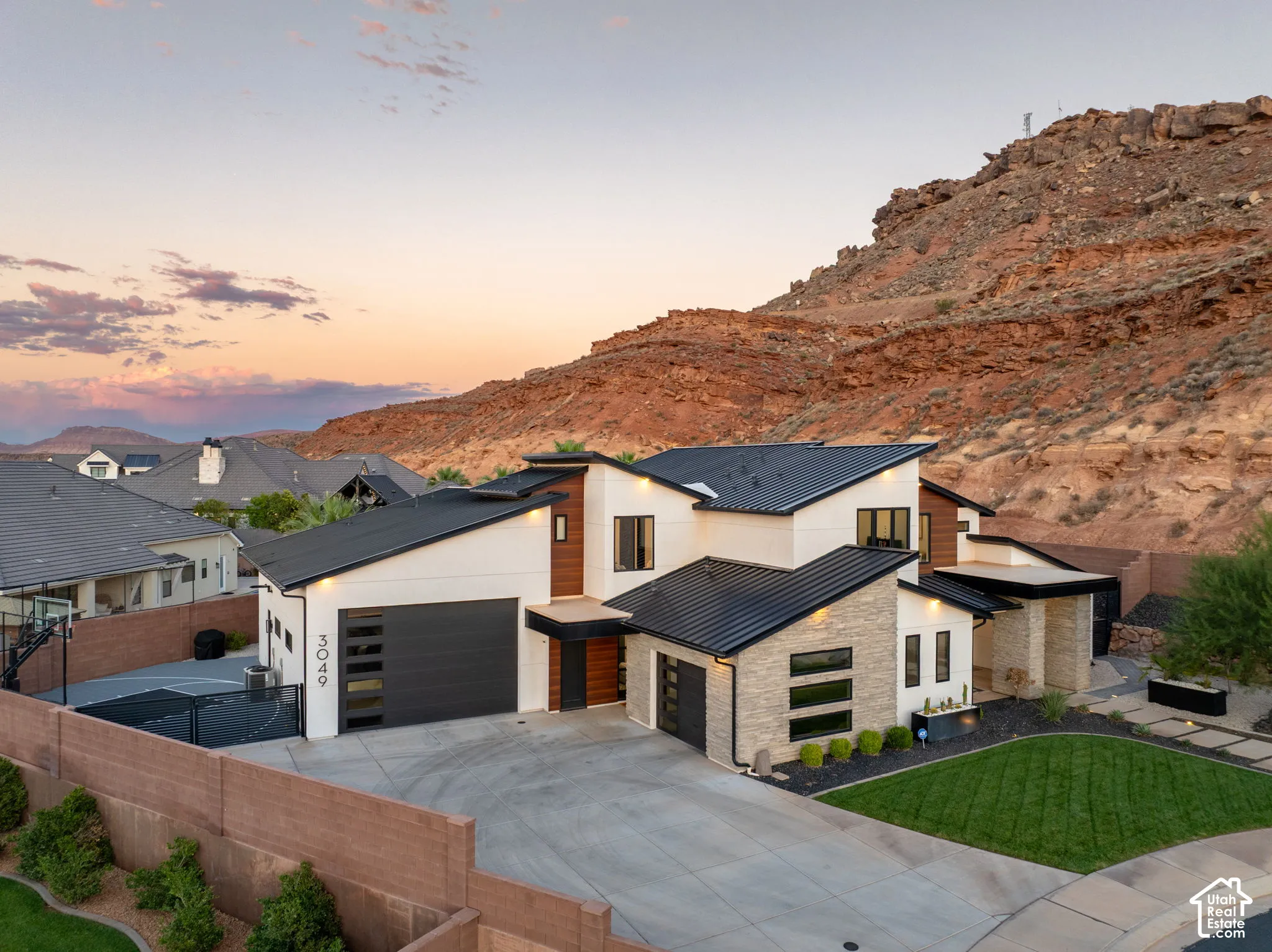 Contemporary multi-level exterior featuring metal roofing, a combination of stucco and stone veneer siding, and a multi-car garage with modern paneled doors