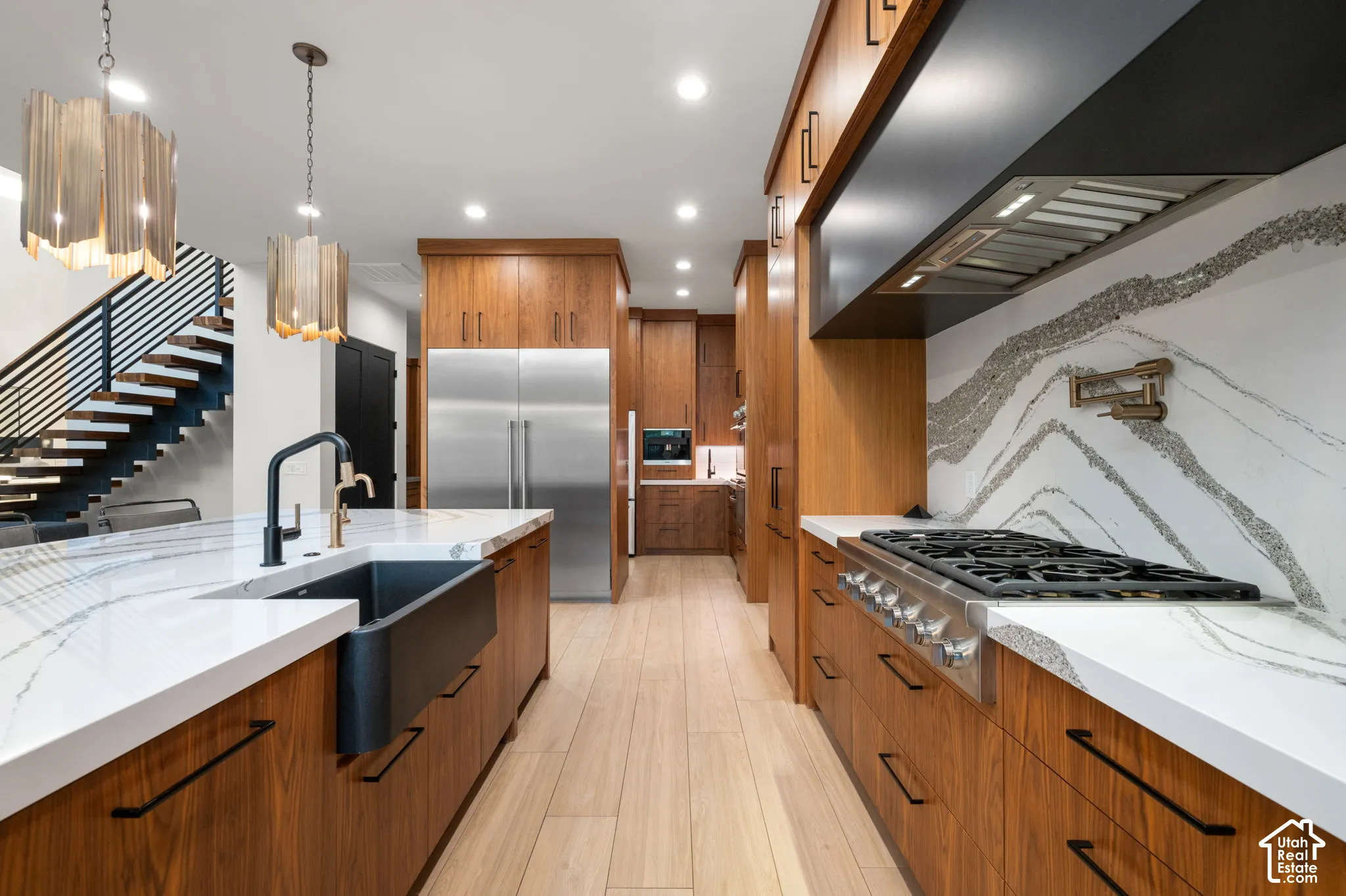 Kitchen featuring wood cabinetry, white stone countertops, a farmhouse-style sink, a professional-grade gas range with a matching vent hood, and wood-finish flooring