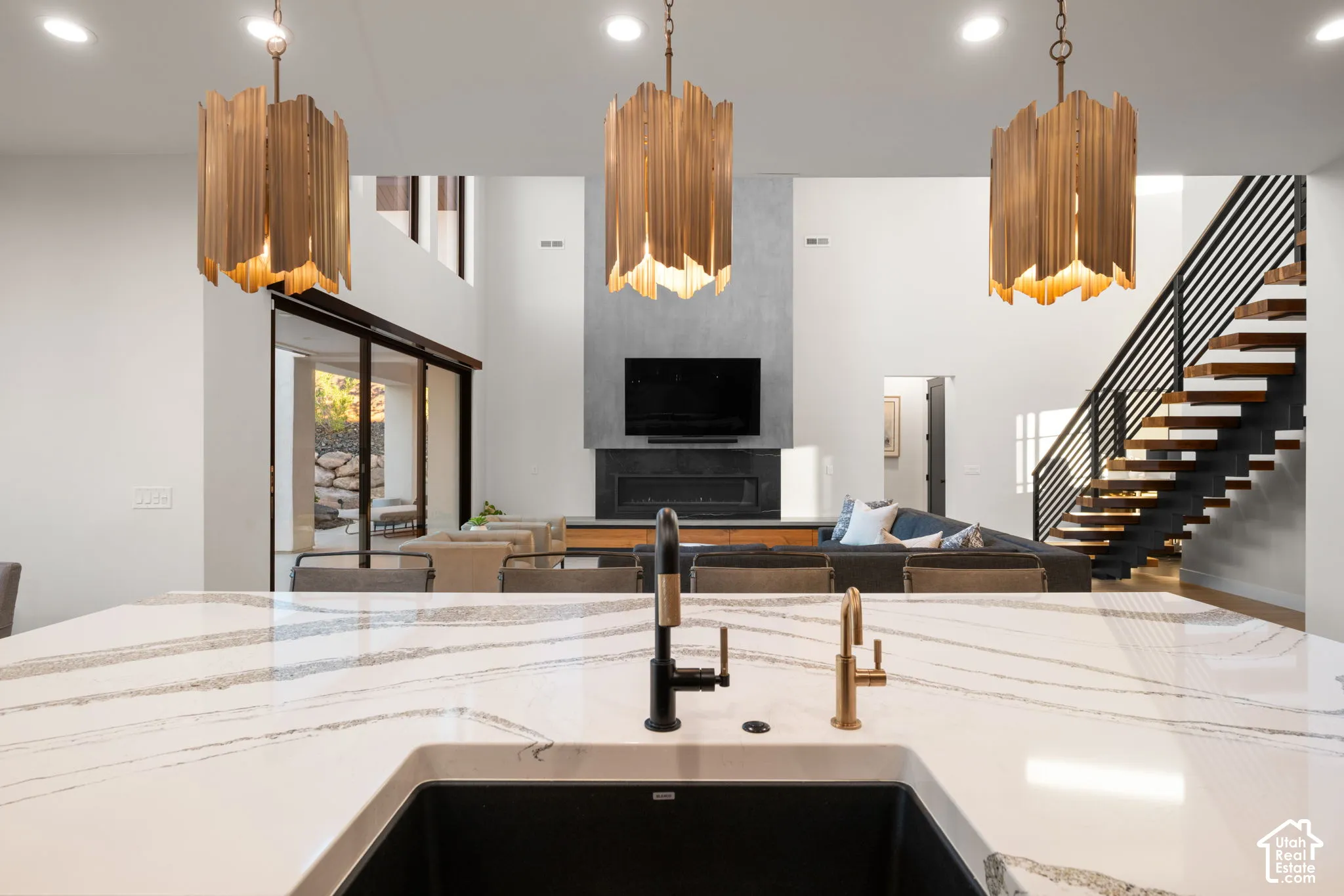 Kitchen island featuring a white surface with grey veining, integrated dark basin sink, and dual-finish faucet fixtures