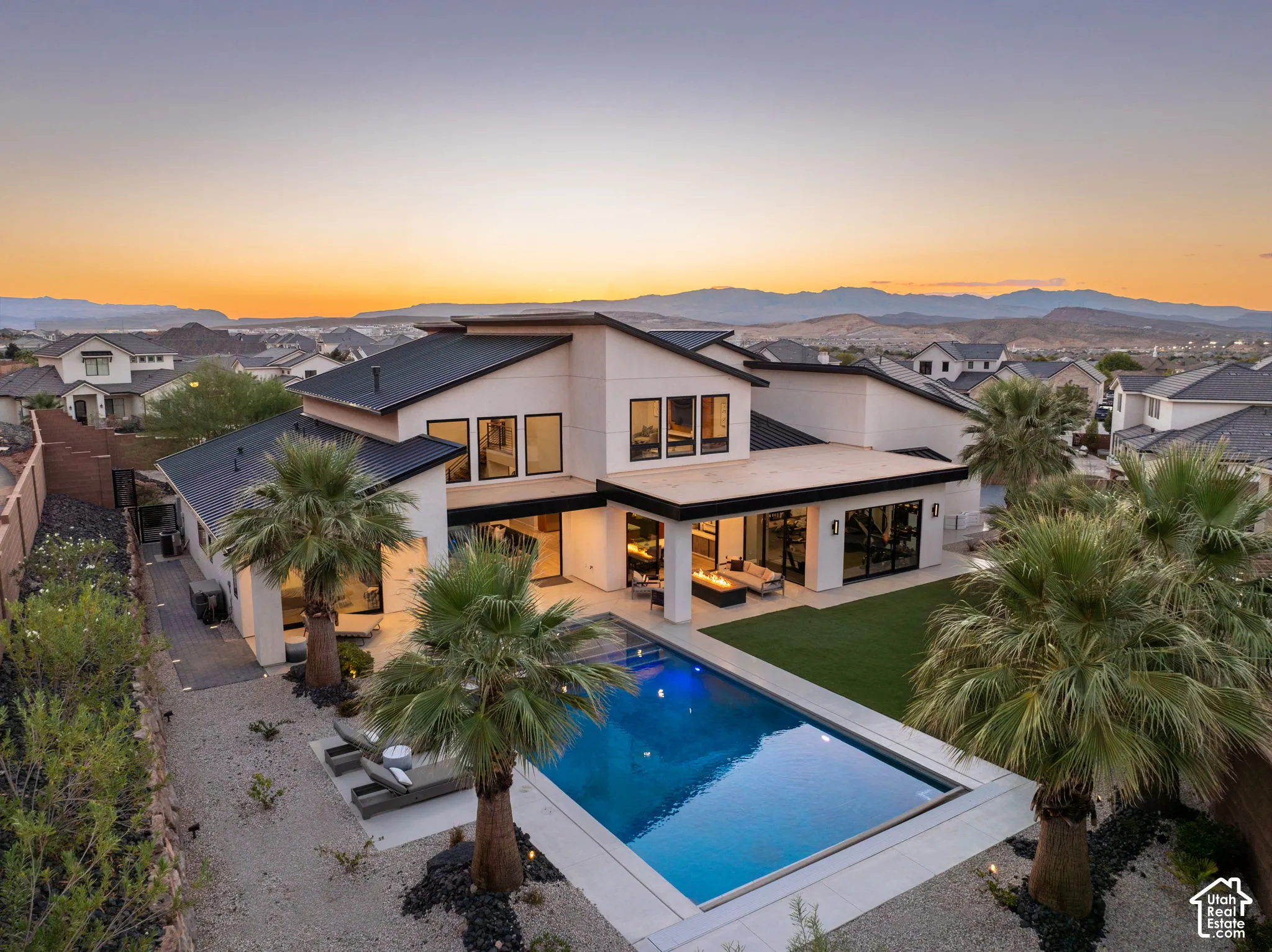 Modern multi-level exterior with a metal roof, swimming pool, manicured lawn, and perimeter landscaping