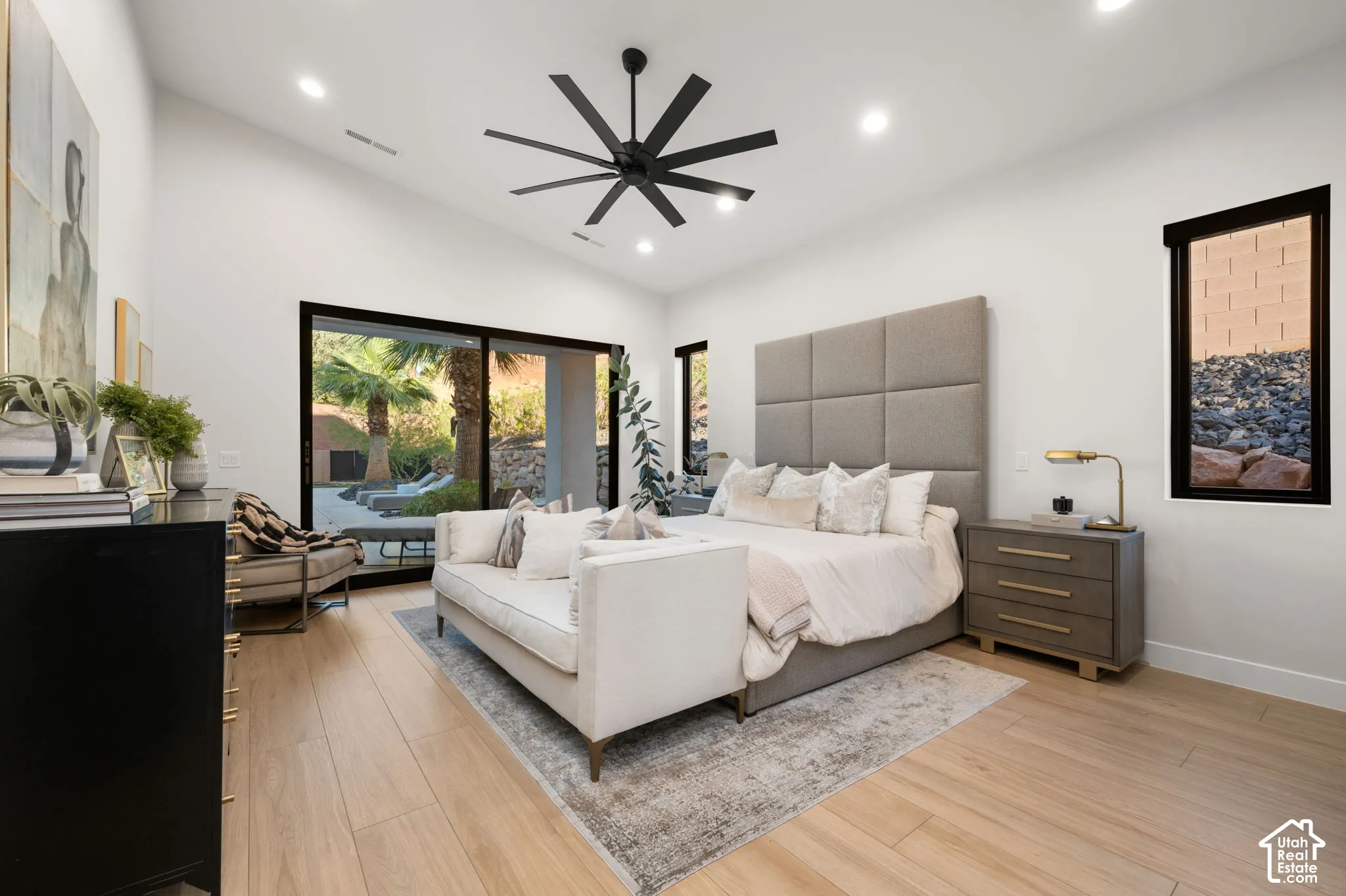 Vaulted ceilings featuring a multi-blade ceiling fan, expansive sliding glass doors, and light-toned wood-finish flooring