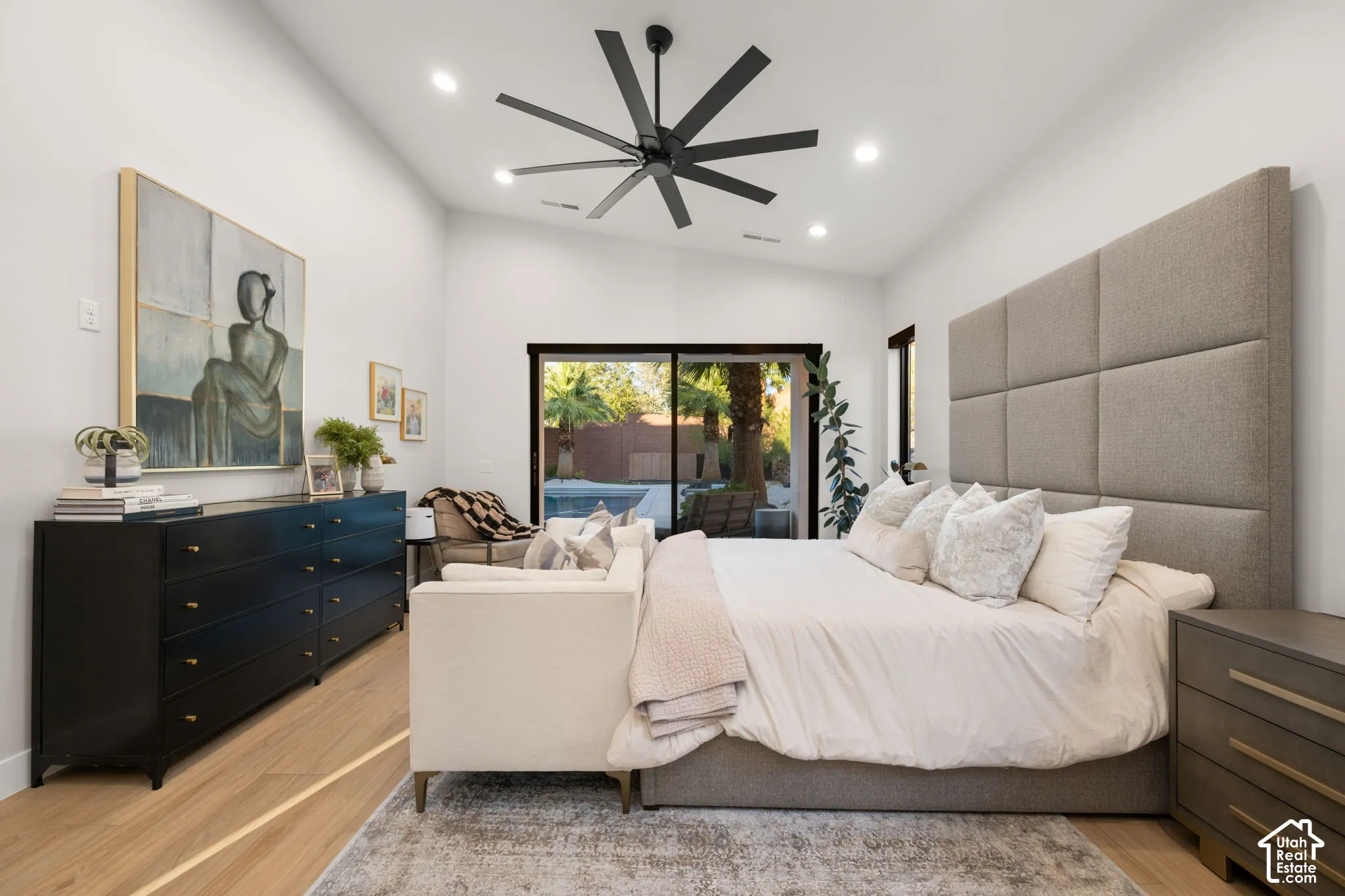 Vaulted ceilings featuring recessed lighting, a modern multi-blade ceiling fan, light-finish wood flooring, and large sliding glass doors