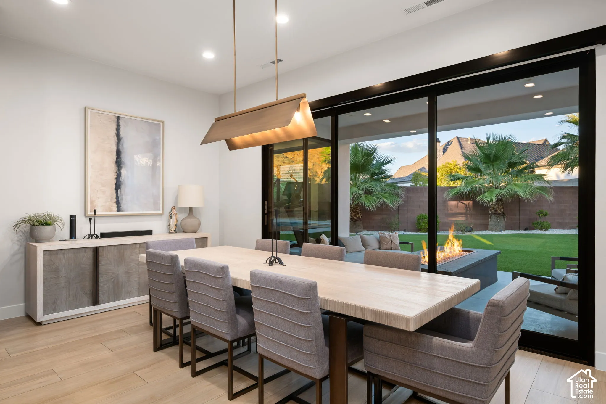 Dining area featuring wood-finish flooring, multi-panel sliding glass doors, recessed lighting, and a linear pendant light fixture