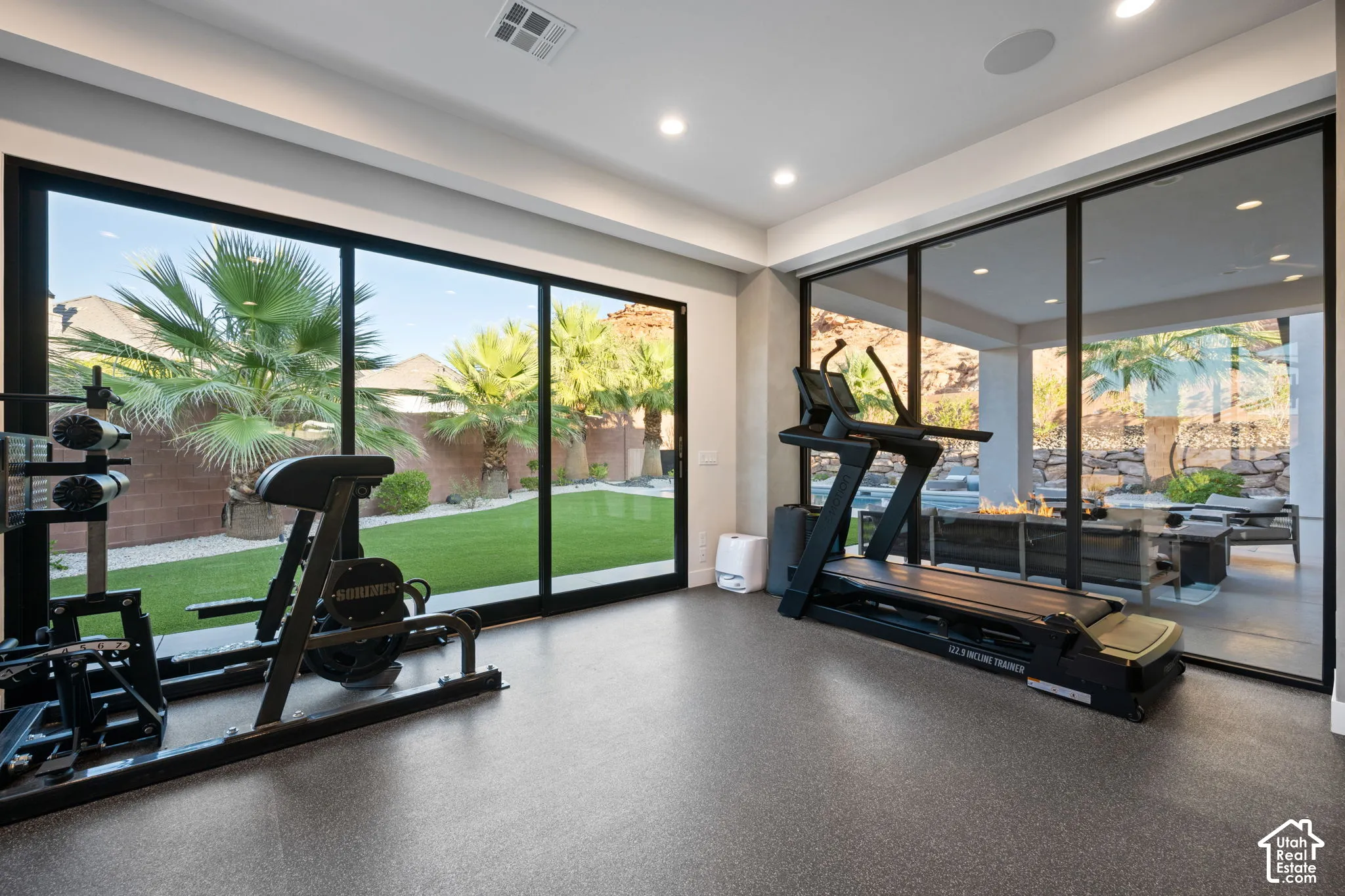 Floor-to-ceiling black-framed glass sliding doors, recessed lighting, textured flooring, and masonry wall