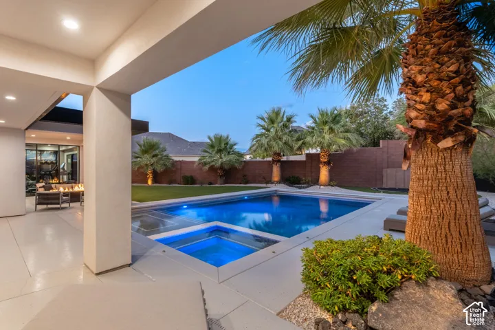 Covered patio with recessed lighting, in-ground pool featuring an integrated spa, concrete decking, and perimeter masonry wall