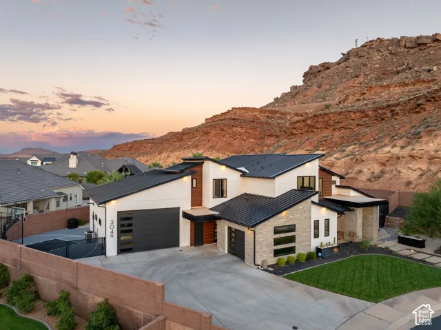 Contemporary multi-level exterior featuring metal roofing, a combination of stucco and stone veneer siding, and a multi-car garage with modern paneled doors