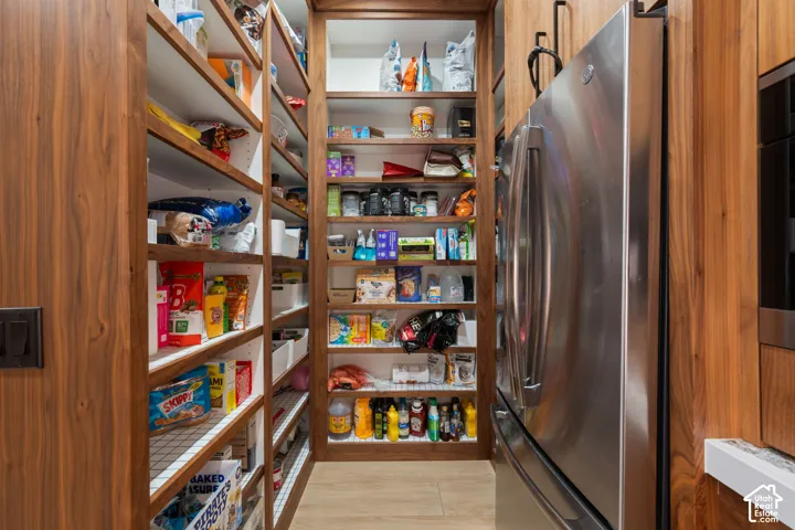 Custom wood-finish shelving, floor-to-ceiling cabinetry, and integrated stainless steel refrigerator