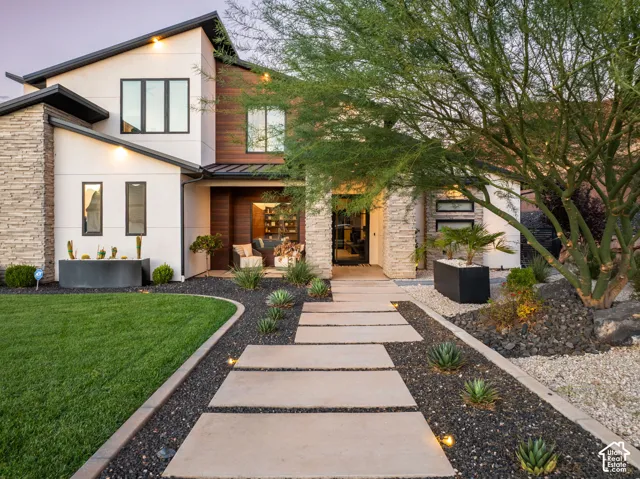 Modern exterior featuring a stucco and horizontal wood-panel facade, stone veneer accents, flat roofline, and a concrete paver walkway