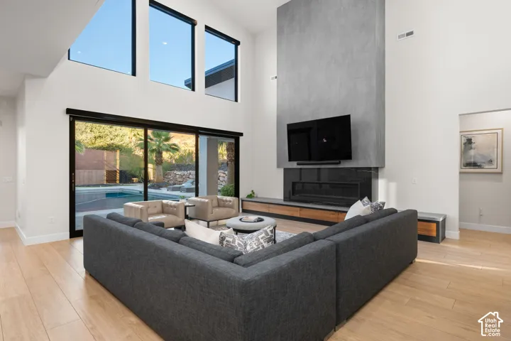 Double-height ceilings featuring floor-to-ceiling windows, full-height masonry fireplace surround, linear gas insert, and wood-finish flooring