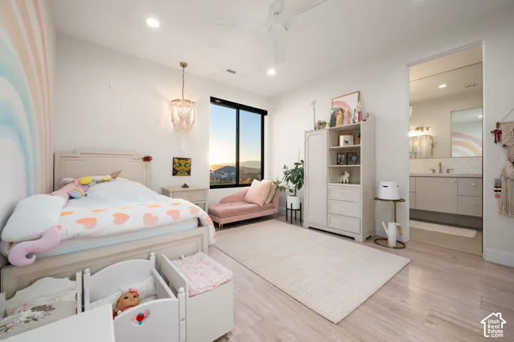 Neutral-toned wood-finish flooring, recessed lighting, white ceiling fan, large window with black frame, and crystal-style pendant lighting