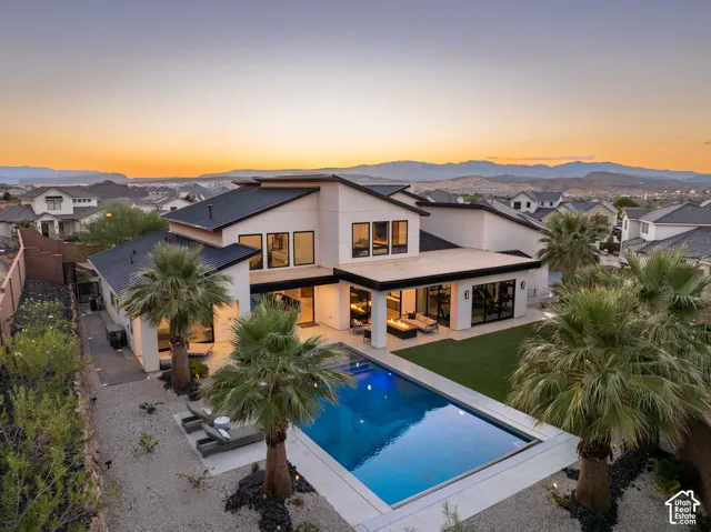 Modern multi-level exterior with a metal roof, swimming pool, manicured lawn, and perimeter landscaping