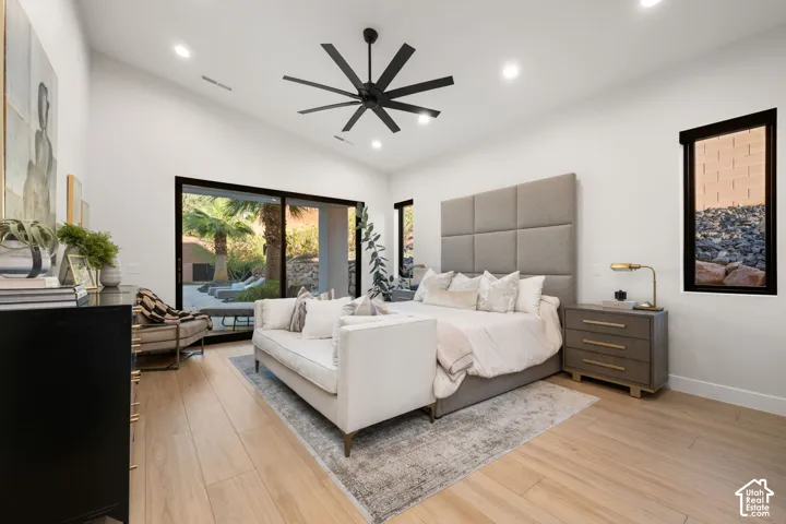 Vaulted ceilings featuring a multi-blade ceiling fan, expansive sliding glass doors, and light-toned wood-finish flooring