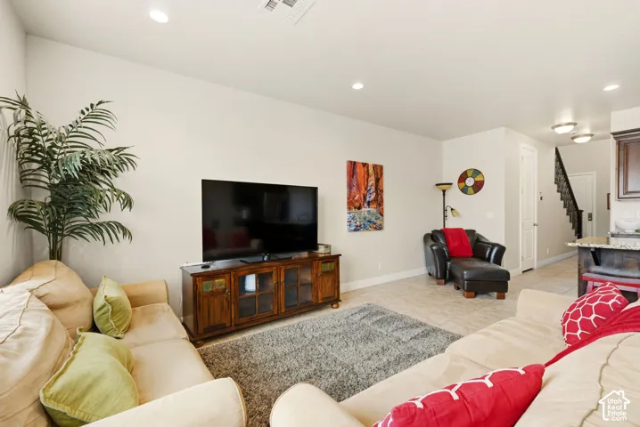 Open-concept interior featuring neutral wall tones, recessed lighting, and large-format tile flooring