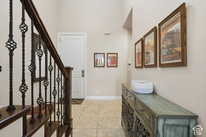 Entryway featuring high ceilings, stone-finish tile flooring, and a staircase with stained wood treads and decorative wrought iron balusters