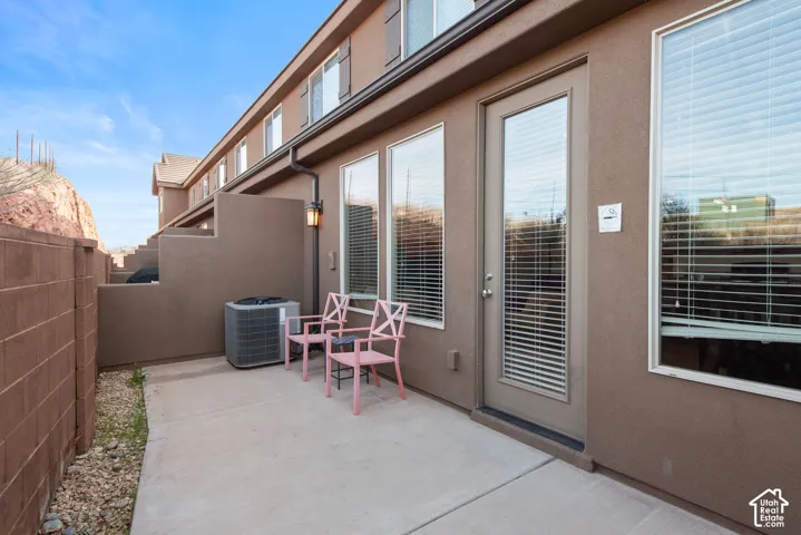 Concrete patio, stucco exterior, masonry perimeter wall, and exterior wall-mounted light fixture