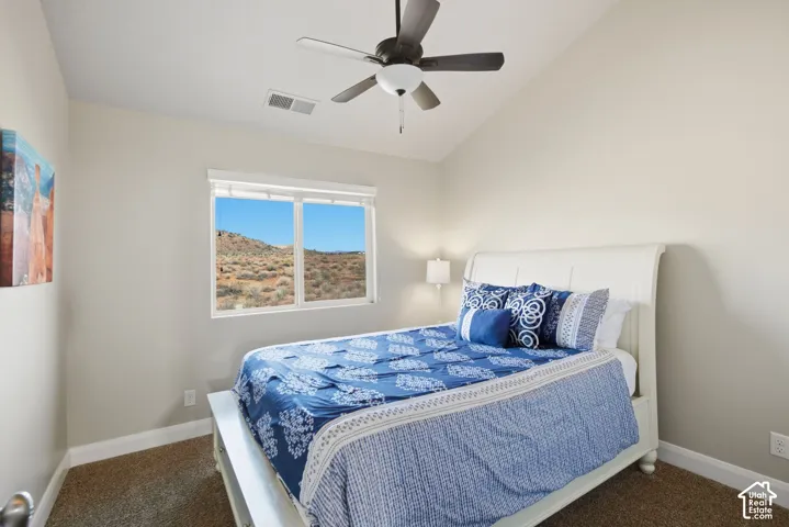 Vaulted ceiling featuring a central multi-blade ceiling fan and neutral wall finish, paired with a large window showcasing a desert landscape