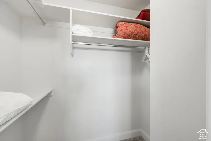 Storage closet featuring built-in shelving, white finish cabinetry, and dual metal clothing rods