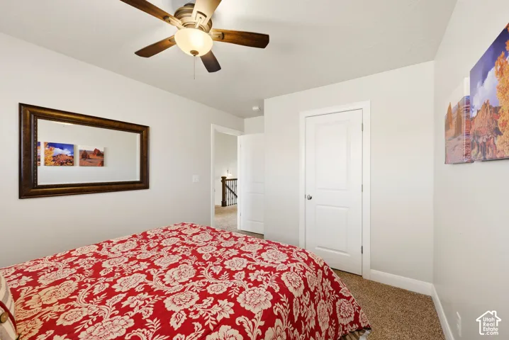Neutral interior walls, carpeted flooring, and a multi-blade ceiling fan with integrated light fixture, featuring a paneled interior door