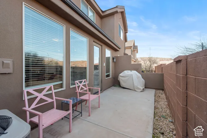 Stucco exterior with a concrete patio, full-height windows, and masonry privacy wall
