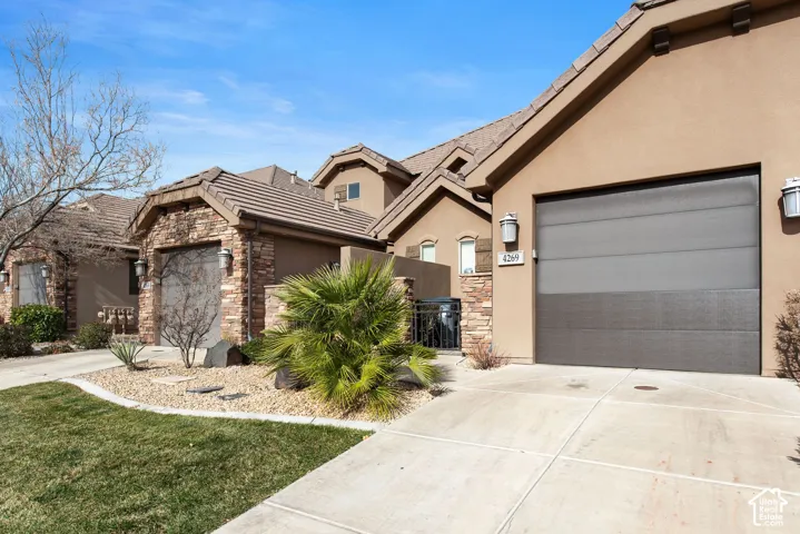 Stucco exterior with stone veneer accents, multi-gabled roofline, concrete driveway, and attached two-car garage