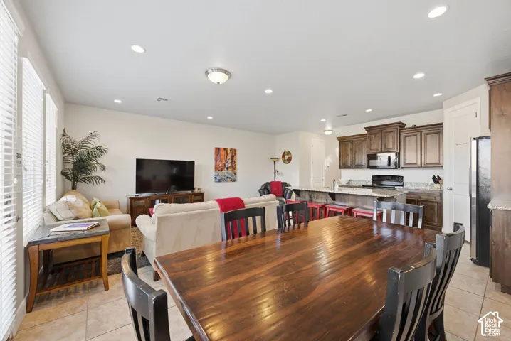 Open-concept area featuring tile flooring, recessed lighting, and kitchen cabinetry with a stone-surfaced breakfast bar