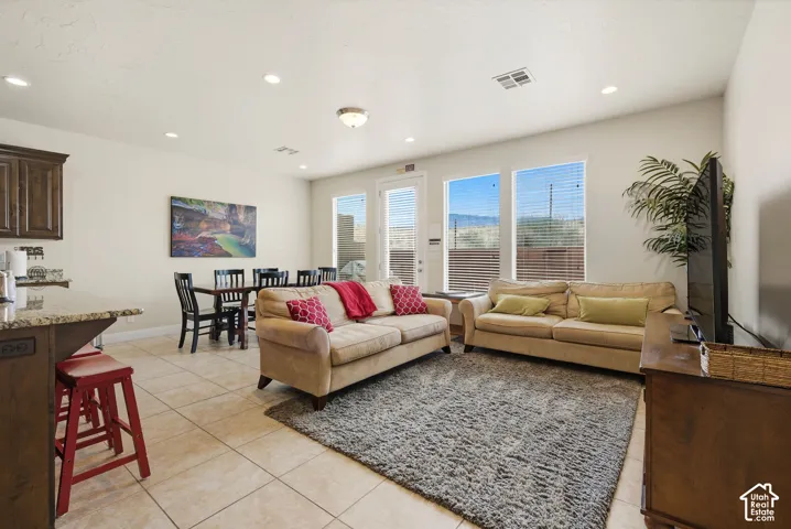 Open-concept area featuring tile flooring, recessed lighting, stone-surfaced kitchen island, and multiple windows providing natural light