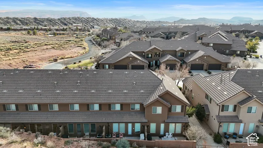 Aerial perspective of a multi-unit residential community featuring brown-toned exterior cladding, multi-pitch rooflines, and desert-inspired landscape topography