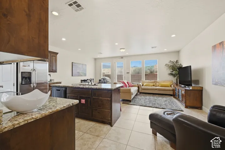 Open-concept interior featuring tile flooring, recessed lighting, and a kitchen island with stone-finish countertops and dark wood cabinetry