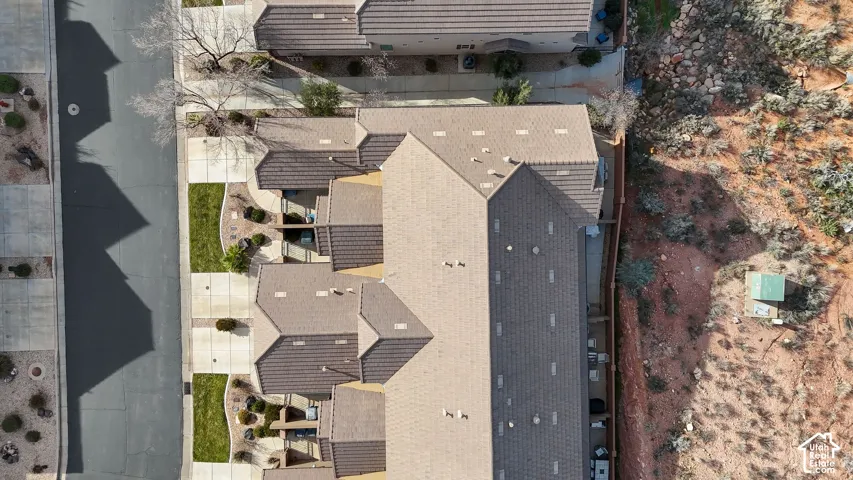 Aerial perspective featuring a multi-unit property with tile roofing, concrete driveways, and landscaped lawn areas