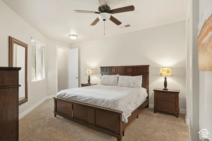 Neutral-toned room featuring wall-to-wall carpeting, a ceiling fan with integrated lighting, and a single-window with horizontal blinds