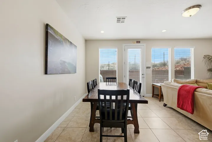 Neutral tile flooring, recessed ceiling lighting, and multiple windows with integrated blinds
