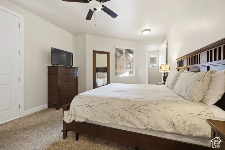 Neutral-toned interior featuring carpeted flooring, a ceiling fan with light fixture, flush-mount lighting, and a single-pane window with horizontal blinds