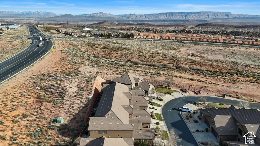 Aerial perspective featuring a multi-unit residential structure with multi-gabled roofing, concrete driveways, and expansive mountain terrain