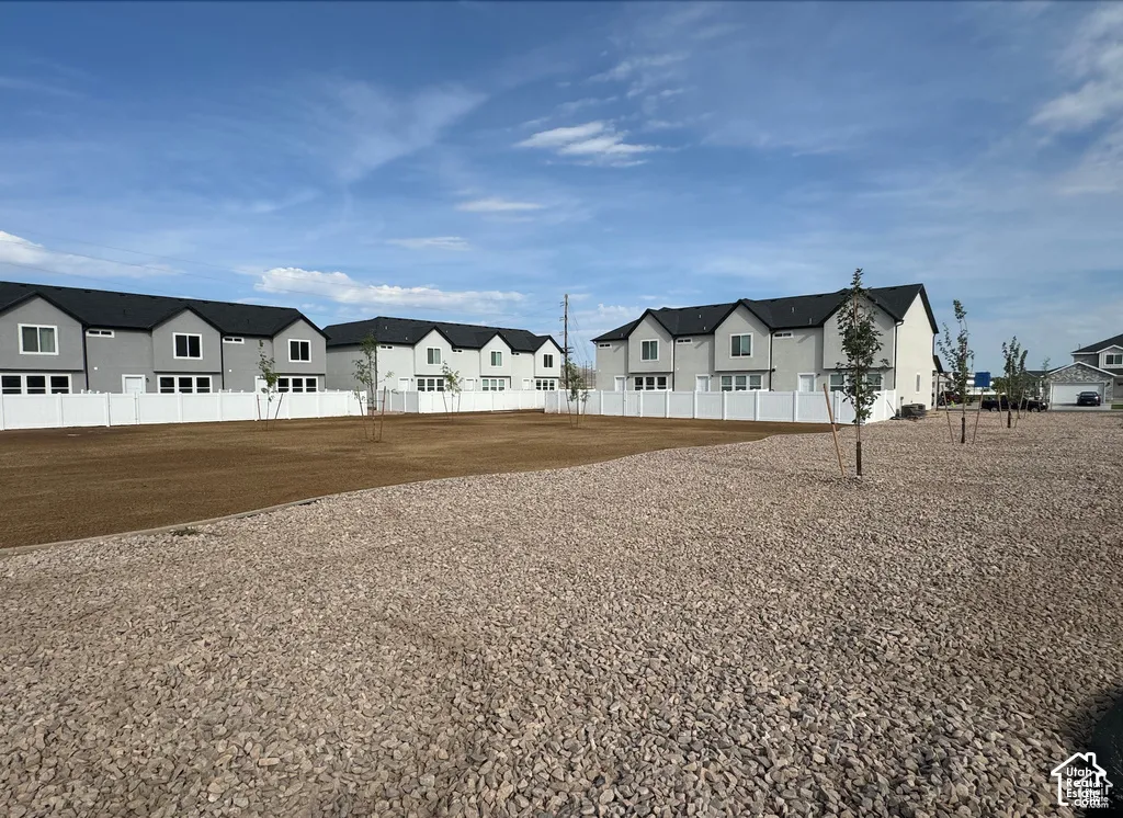 Expansive exterior space featuring a split-surface lawn and gravel landscaping, enclosed by white vinyl privacy fencing