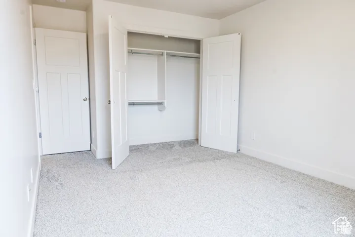 Neutral carpeted flooring, two-panel shaker-style interior doors, and a built-in reach-in closet featuring integrated shelving and hanging rods