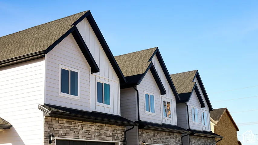 Exterior elevation featuring multi-gabled rooflines, vertical and horizontal siding, stone veneer accents, and roof-mounted gutters