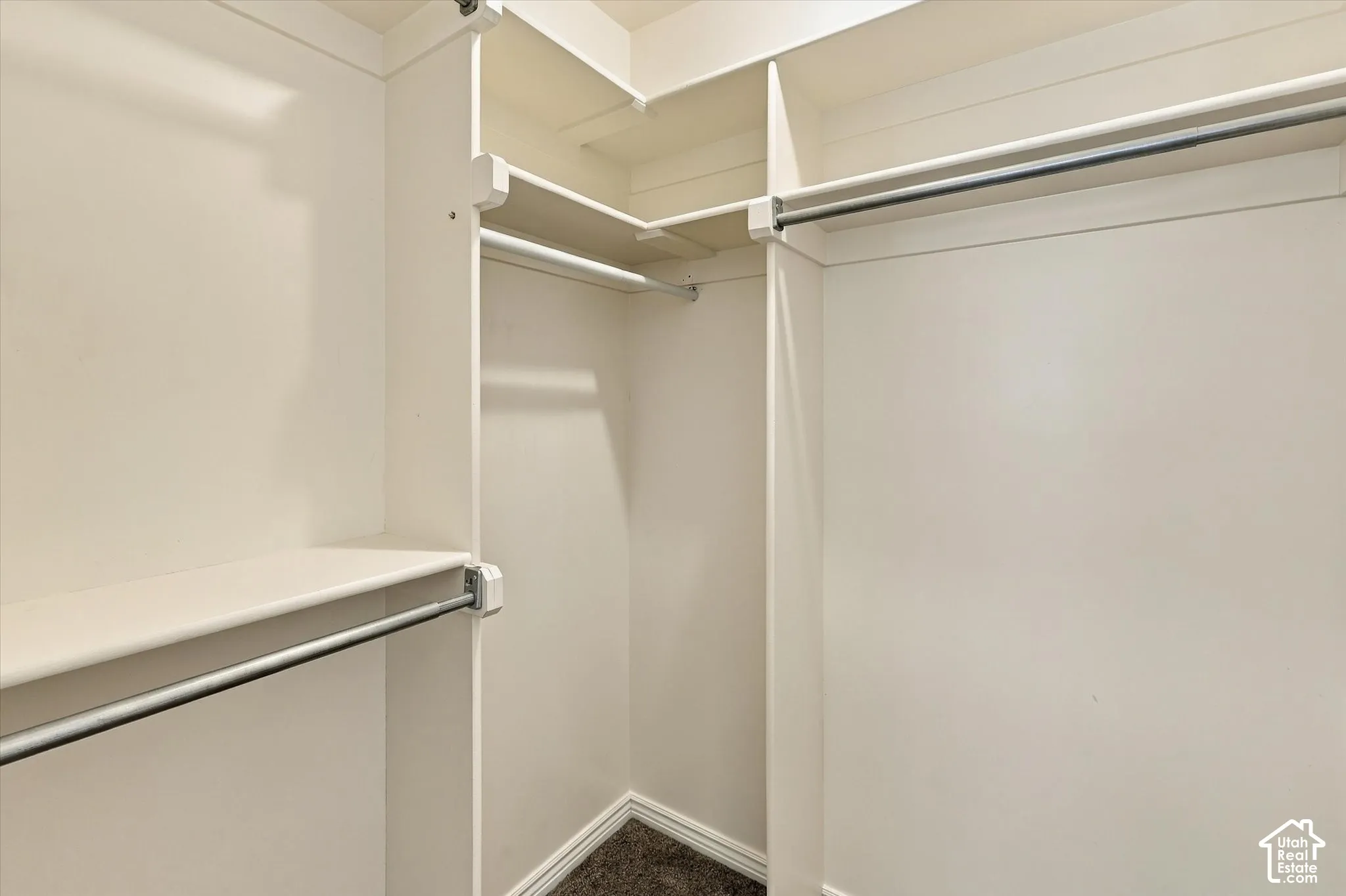 Walk-in closet featuring white built-in shelving, tiered organization levels, and metal hanging rods