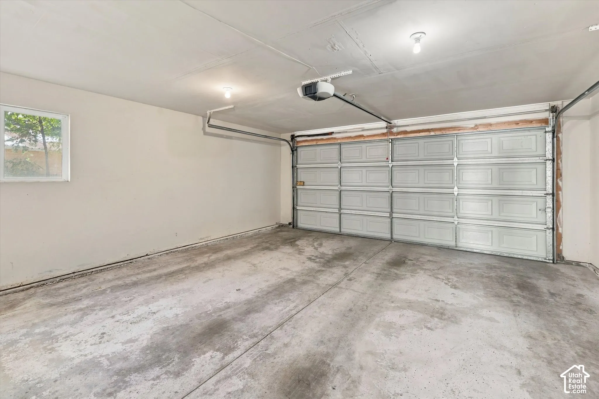 Two-car garage featuring a sectional overhead door, concrete flooring, and an automated garage door opener