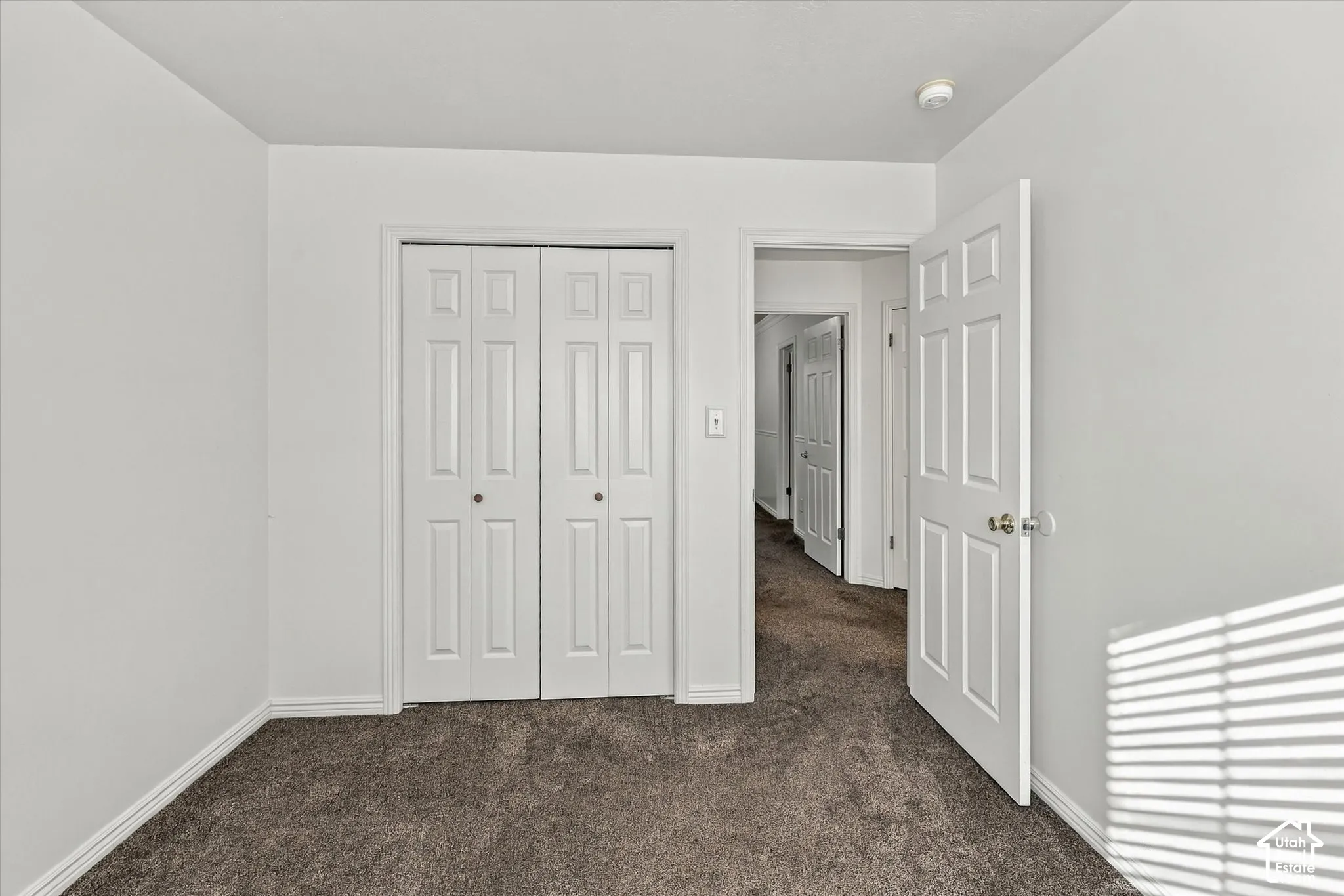 Room featuring neutral wall finishes, carpeting, two-panel interior doors, and a double-panel bifold closet door