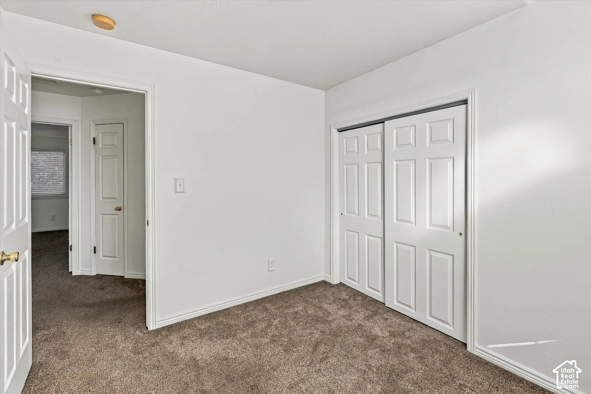 Neutral-toned carpeting, white walls, and interior doors featuring six-panel detailing and sliding closet access