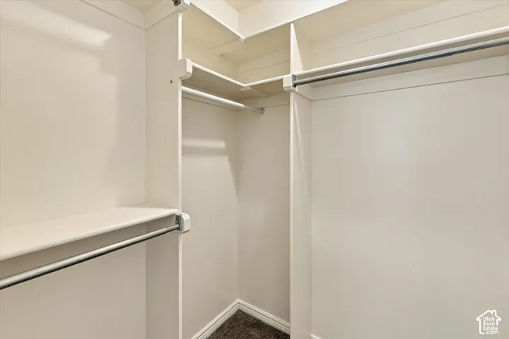 Walk-in closet featuring white built-in shelving, tiered organization levels, and metal hanging rods