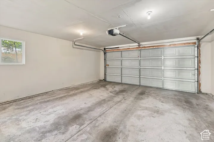 Two-car garage featuring a sectional overhead door, concrete flooring, and an automated garage door opener